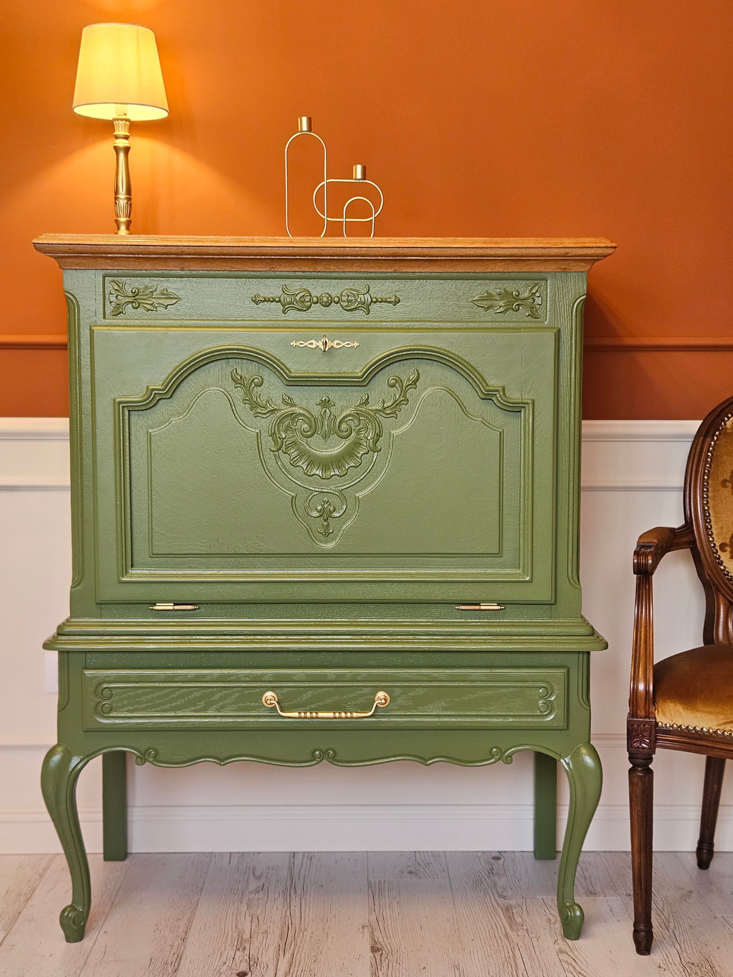 Bar verde vintage cu blat din lemn, decorat cu lampă aurie și suport minimalist pentru lumânări.