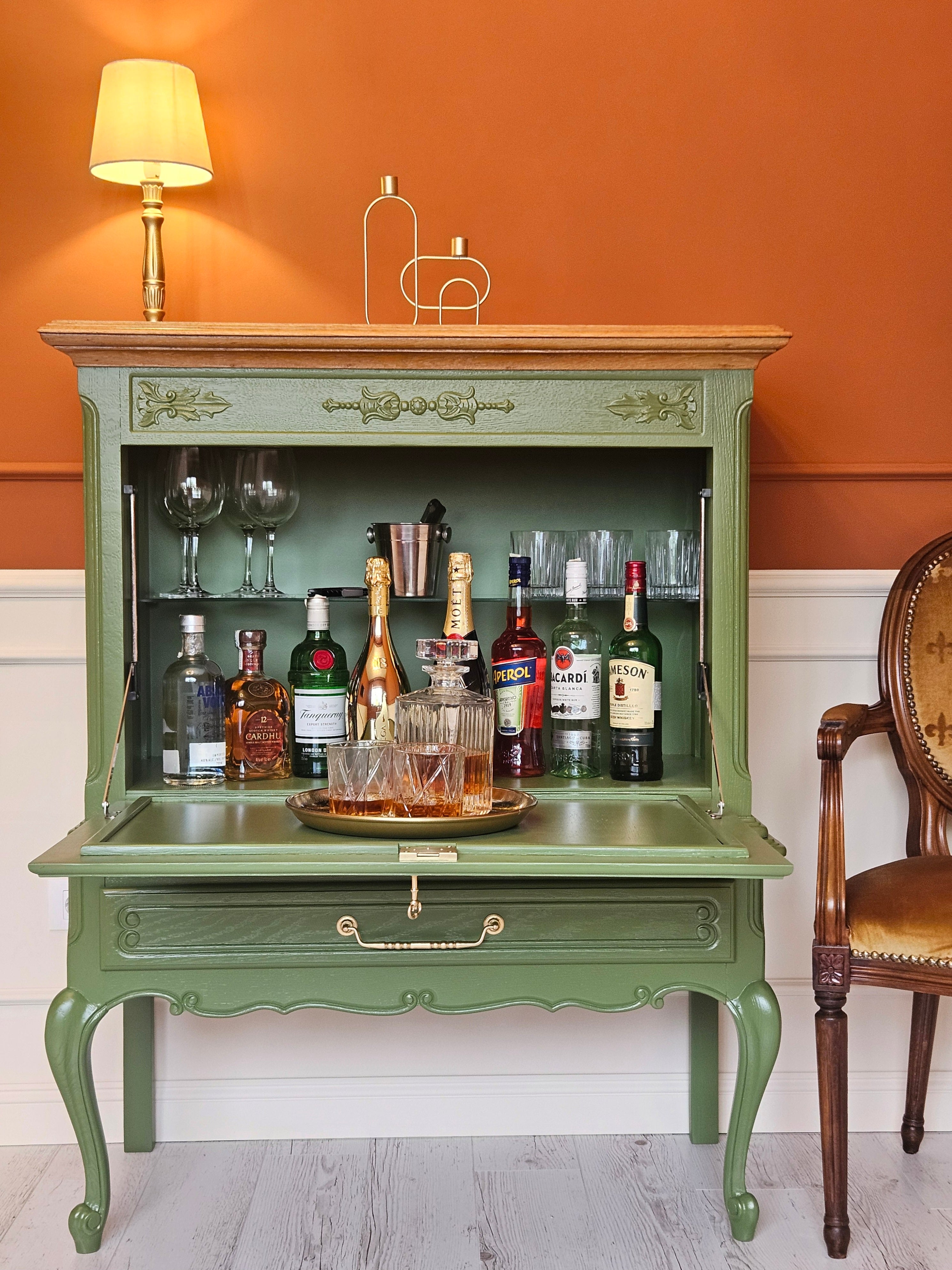 Bar vintage recondiționat, transformat în minibar cu sticle de băuturi și pahare de cristal.