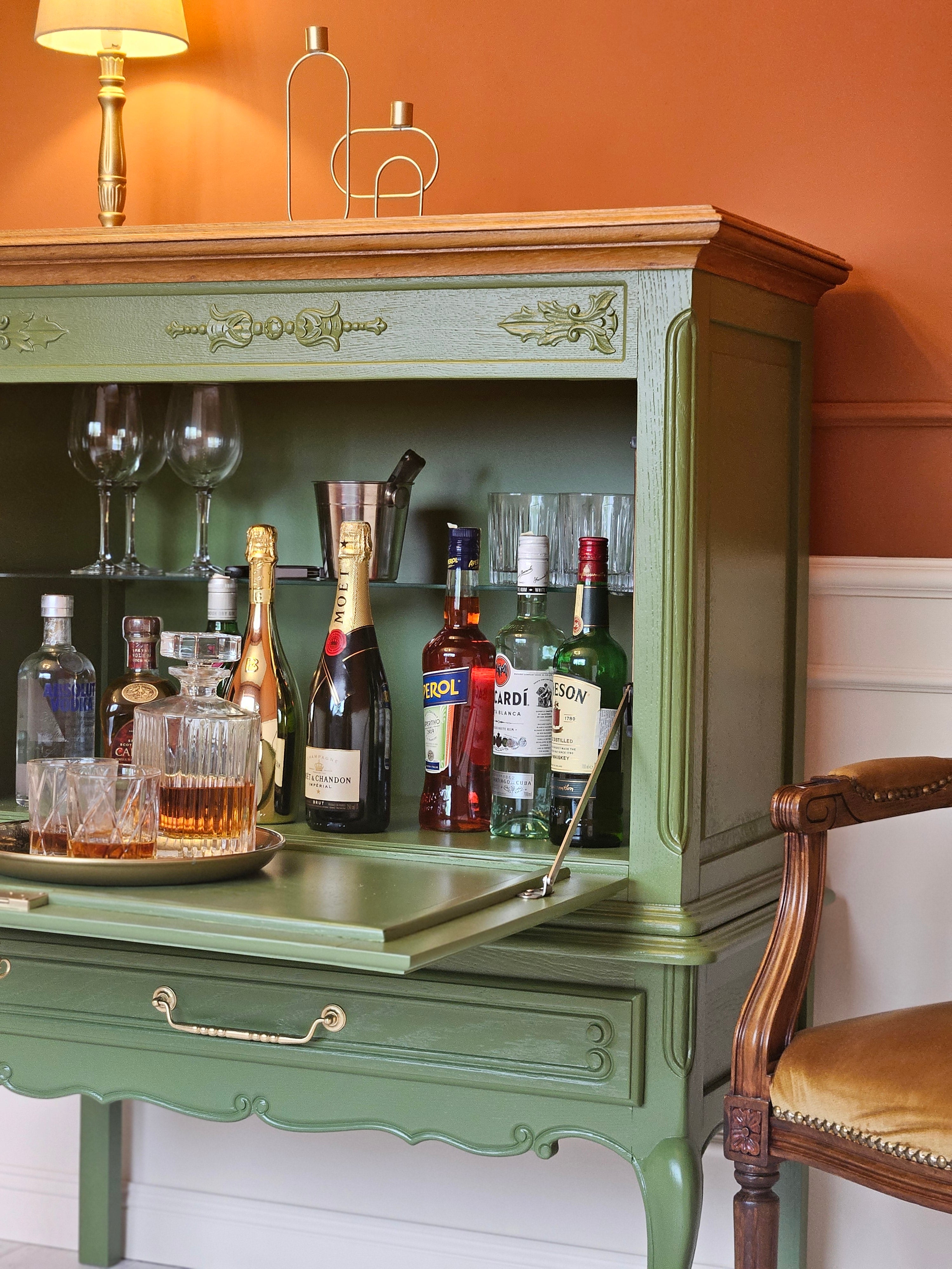 Detaliu cu un bar verde vintage deschis, prezentând sticle de băuturi premium expuse.