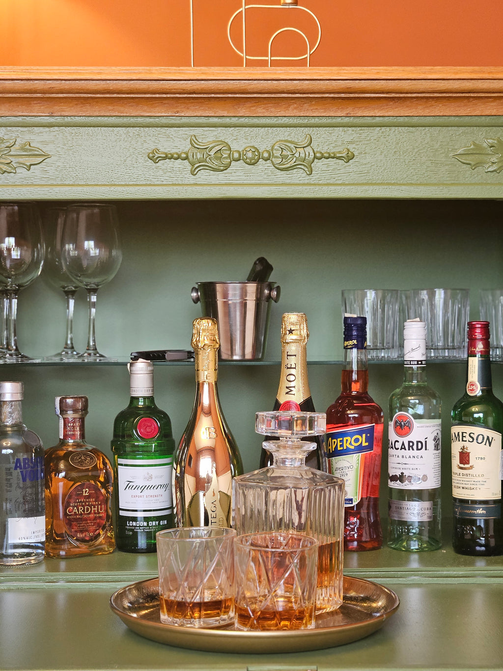 Bar vintage recondiționat, cu tavă aurie, sticle de șampanie și pahare de cristal, într-un decor clasic.