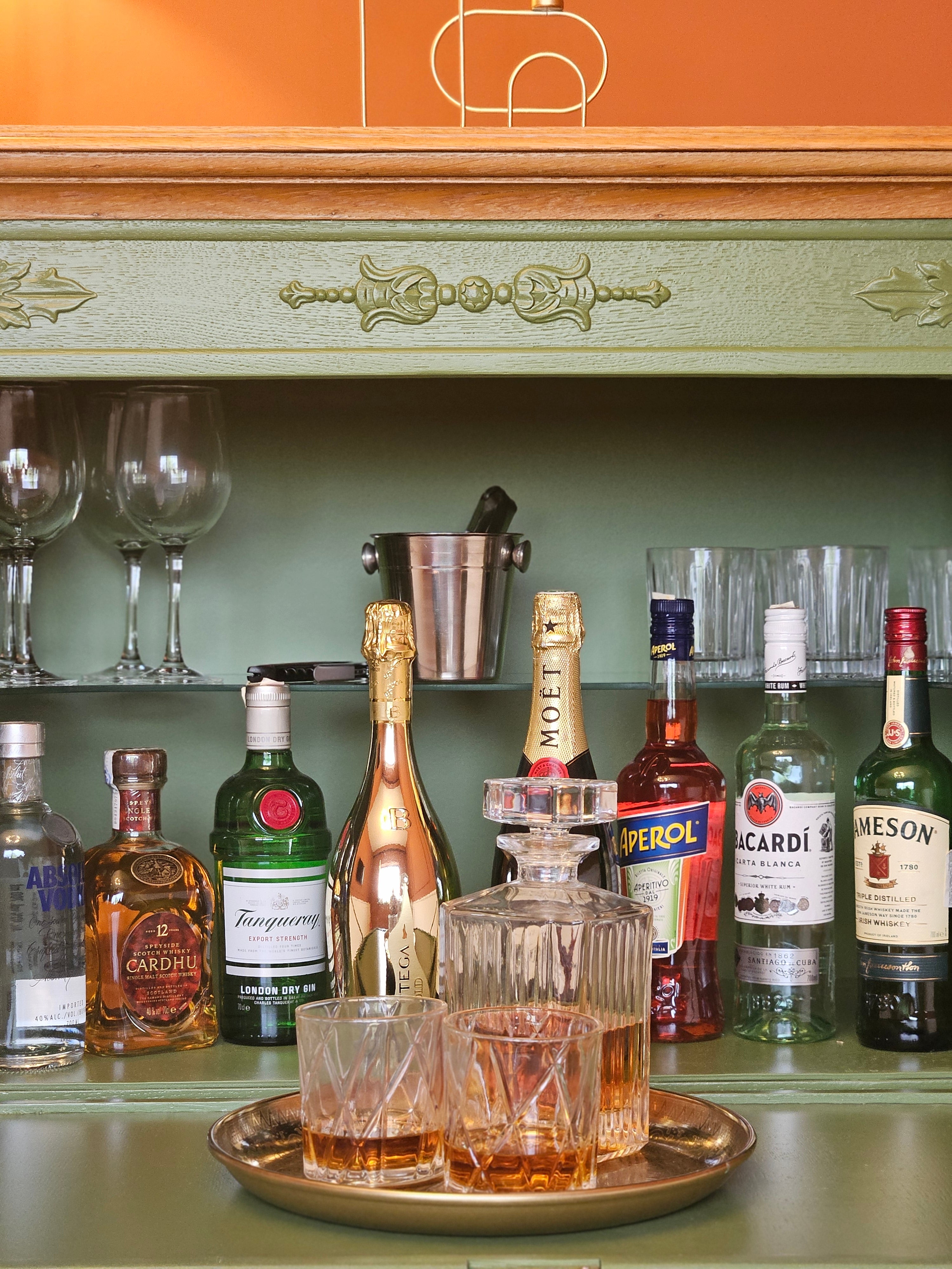 Bar vintage recondiționat, cu tavă aurie, sticle de șampanie și pahare de cristal, într-un decor clasic.