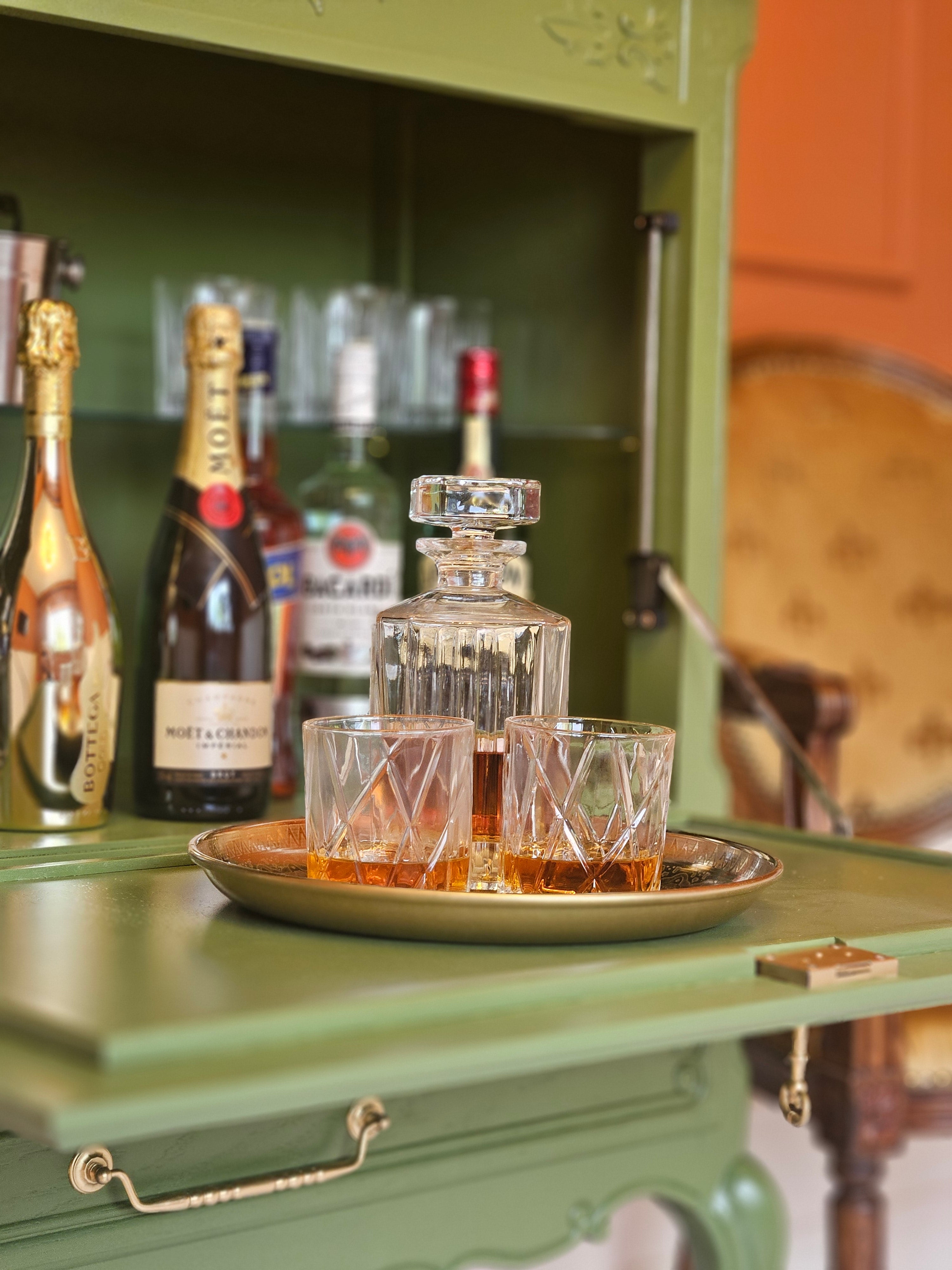 Bar vintage recondiționat, cu tavă aurie, sticle de șampanie și pahare de cristal, într-un decor clasic.