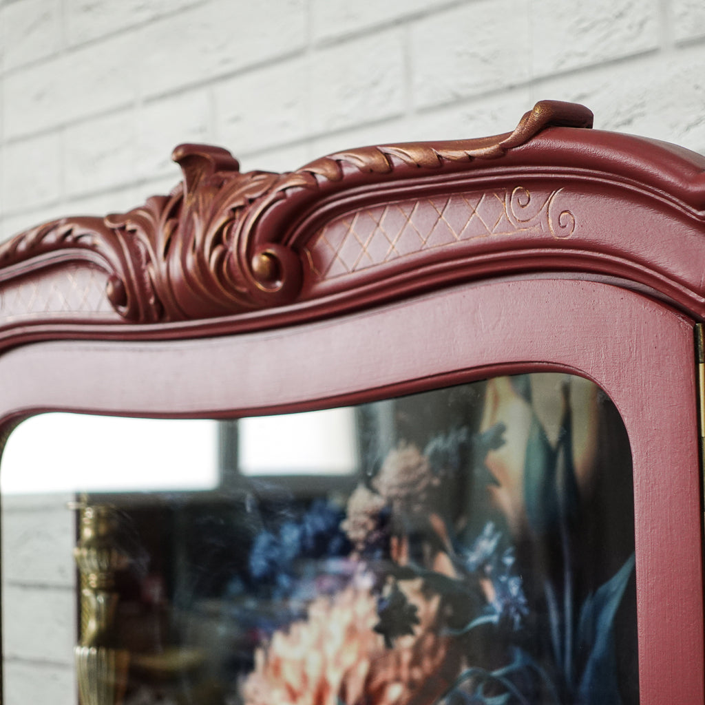 Vitrină vintage burgundy cu detaliu auriu și fundal floral, mobilier recondiționat elegant.
